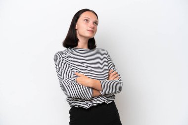 Beyaz arka planda izole edilmiş genç beyaz kadın gülümserken yukarı bakıyor.