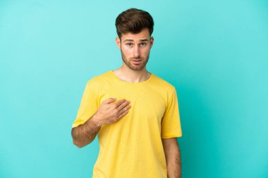 Mavi arka planda soyutlanmış beyaz tenli yakışıklı bir adam kendini işaret ediyor.