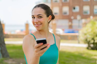 Açık havada cep telefonu kullanan genç ve güzel bir kadın.