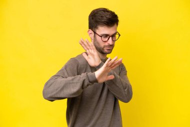 Sarı arka planda izole edilmiş genç beyaz adam sinirleri öne doğru geriliyor.