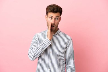 Pembe arka planda izole edilmiş beyaz yakışıklı bir adam. Yan tarafa bakarken sürpriz bir jest yapıyor.