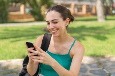 Dışarıda cep telefonu kullanan genç ve güzel bir kadın.