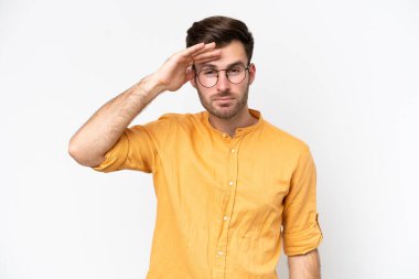 Beyaz arka planda izole edilmiş genç beyaz bir adam bir şeye bakmak için çok uzaklara bakıyor.