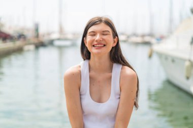 Genç, güzel bir kadın açık havada, mutlu bir ifadeyle.