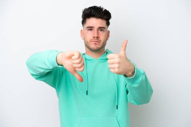 Beyaz arka planda izole edilmiş beyaz bir adam iyiye-kötüye işaret yapıyor. Evet ya da hayır arasında kararsız