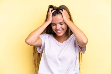 Sarı arka planda izole edilmiş genç beyaz kadın gülüyor.