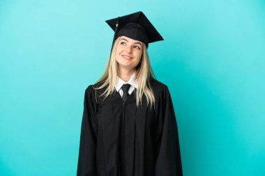 Tecrit edilmiş mavi arka planda genç üniversite mezunu.