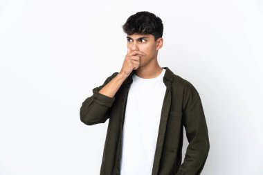 İzole edilmiş beyaz arka planda genç bir adam yan tarafa bakarken sürpriz jest yapıyor.