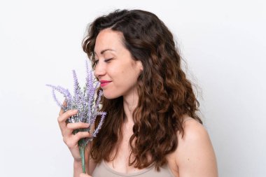 Beyaz arka planda, lavanta bitkisi tutan beyaz tenli genç bir kadın. Portreyi kapat