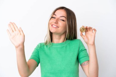 Elinde Bitcoin tutan genç Romen kadın beyaz arka planda izole edilmiş mutlu bir ifadeyle selamlıyor