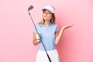 Pembe arka planda izole edilmiş genç golfçü kadın ellerini kaldırırken şüpheleri var.