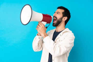 Mavi arka planda beyaz kadife ceketli yakışıklı genç adam megafondan bağırıyor.