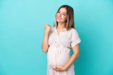 Genç Romen kadın mavi arka planda izole edilmiş hamile ve başparmağı yukarıda