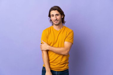 Mor arka planda yalnız, yakışıklı bir adam gülüyor.