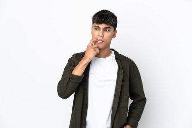 Soyutlanmış beyaz arka plandaki genç adam gergin ve korkmuş.