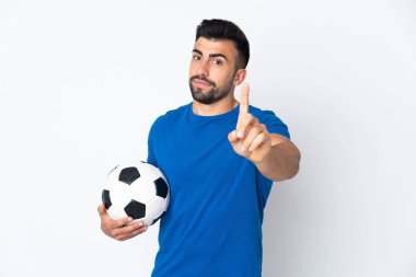 Yakışıklı genç futbolcu, izole olmuş duvarın üzerinden parmağını kaldırıyor.