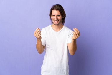 Mor arka planda izole genç yakışıklı adam para hareketi yapıyor.