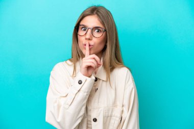 Mavi arka planda gözlüklü, sessiz hareketler yapan beyaz bir kadın.