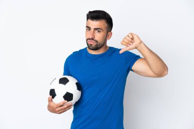 Yakışıklı genç futbolcu, izole edilmiş duvarın üzerinden başparmağıyla olumsuz ifade gösteriyor.