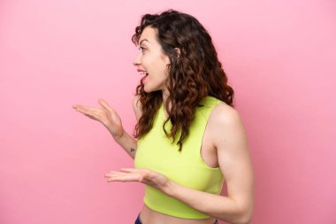 Pembe arka planda mahsur kalmış beyaz bir kadın. Sürpriz bir ifadeyle yan yana bakarken.