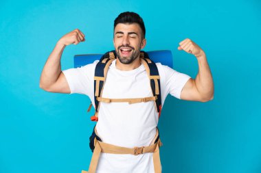 Genç dağcı, izole edilmiş mavi arka planda güçlü bir hareket yapıyor.