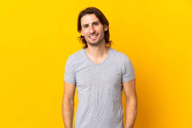 Sarı arka planda yalnız yaşayan yakışıklı bir adam gülüyor.