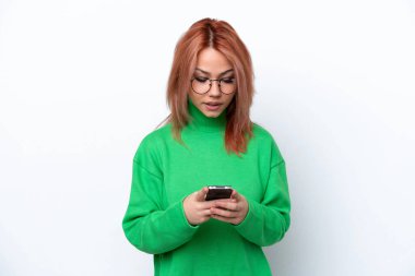 Beyaz arka planda izole edilmiş genç bir Rus kız cep telefonuyla mesaj gönderiyor.