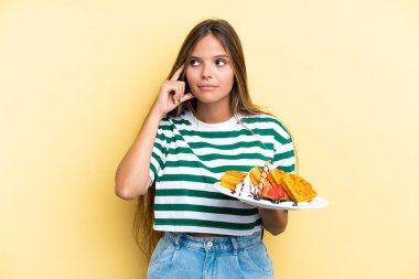 Sarı arka planda gözleme tutan Kafkasyalı genç bir kadın şüpheleri ve düşünceleri var.