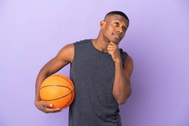 Genç basketbolcu latin adam mor arka planda izole edilmiş ve yukarı bakıyor