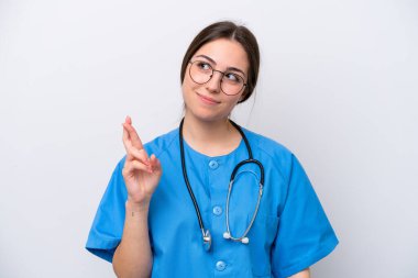 Doktor kadın beyaz arka planda izole edilmiş aletler tutuyor. Parmakları çapraz ve en iyisini diliyor.