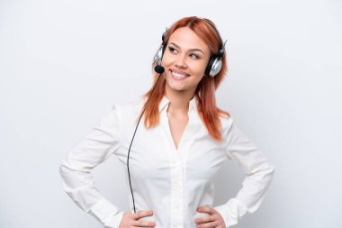 Beyaz arka planda izole edilmiş, kolları kalçasında ve gülümseyen bir kulaklıkla çalışan pazarlamacı Rus kız.