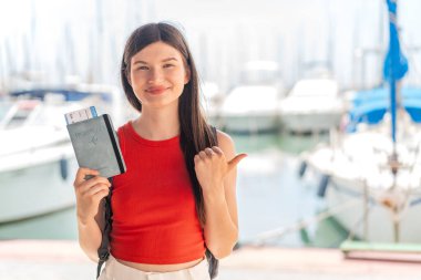 Genç, güzel Ukraynalı bir kadın elinde pasaport tutarak yan tarafı göstererek bir ürün sunuyor.