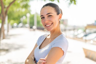 Dışarıda kolları bağlı ve ileriye bakan genç ve güzel bir kadın.