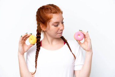 Kırmızımsı genç bir kadın beyaz arka planda izole edilmiş. Elinde donut var.