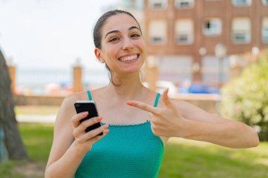 Açık havada cep telefonu kullanan genç ve güzel bir kadın.