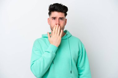 Beyaz arka planda izole edilmiş beyaz tenli genç bir adam ağızı eliyle kapatıyor.