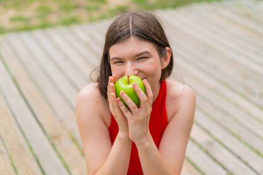 Açık havada elinde elma tutan güzel bir kadın.