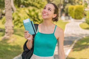 Pasaportu elinde tutan güzel bir kadın gülümserken yukarı bakıyor.