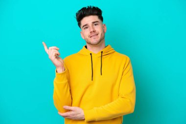 Mavi arka planda izole edilmiş genç beyaz adam mutlu ve dik duruyor.