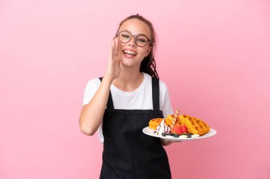Restoran garsonu elinde waffle tutan Rus kız pembe arka planda ağzı açık bağırıyor.