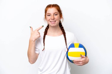 Beyaz arka planda izole bir şekilde voleybol oynayan beyaz tenli genç bir kadın baş parmak hareketi yapıyor.