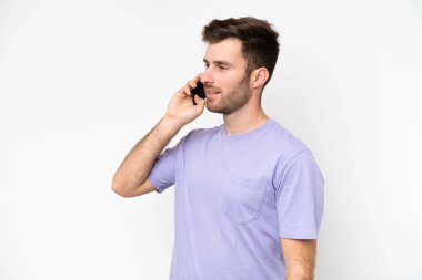Beyaz arka planda izole edilmiş genç beyaz bir adam cep telefonuyla sohbet ediyor.