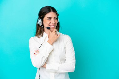 Tele pazarlamacı İtalyan kadın mavi arka planda izole edilmiş bir kulaklıkla çalışıyor.