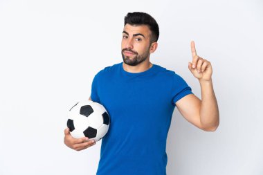 Yakışıklı genç futbolcu, izole edilmiş duvarın üzerinden en iyinin işareti olarak parmağını kaldırıyor.