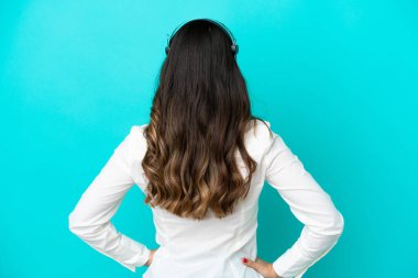 Tele pazarlamacı İtalyan kadın arka planda mavi arka planda izole edilmiş bir kulaklıkla çalışıyor.