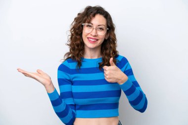 Beyaz arka planda izole edilmiş genç beyaz bir kadın bir ilan vermek ve onaylamak için avucunun içinde hayali bir mekan tutuyor.