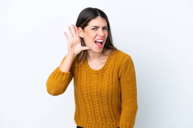 Genç İtalyan kadın beyaz arka planda izole edilmiş bir şekilde bir şeyler dinlerken elini kulağına koyar.