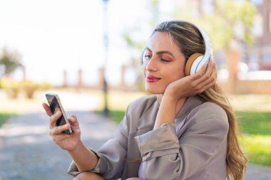 Açık havada cep telefonu kullanan güzel sarışın Uruguaylı kadın.