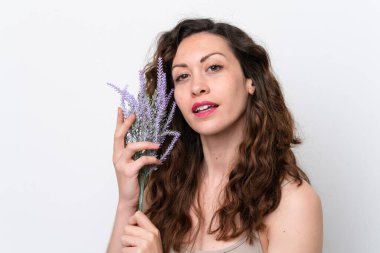 Beyaz arka planda, lavanta bitkisi tutan beyaz tenli genç bir kadın. Portreyi kapat