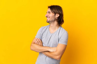 Sarı arka planda izole edilmiş genç yakışıklı adam mutlu ve gülümsüyor.